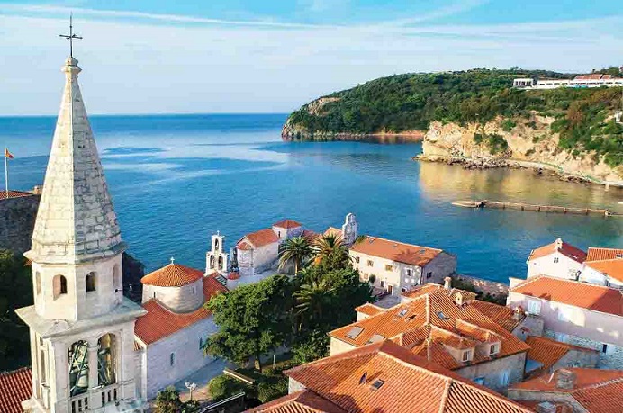 Budva Old Town View with beach behind. Beautiful roofs of Budva Old town houses are visible, with church dominating the view.